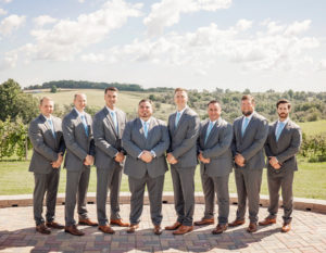 Groom with his groomsmen on the wedding platform before a summer wedding by the vineyard at Pedretti's Party Barn in Viroqua, Wisconsin